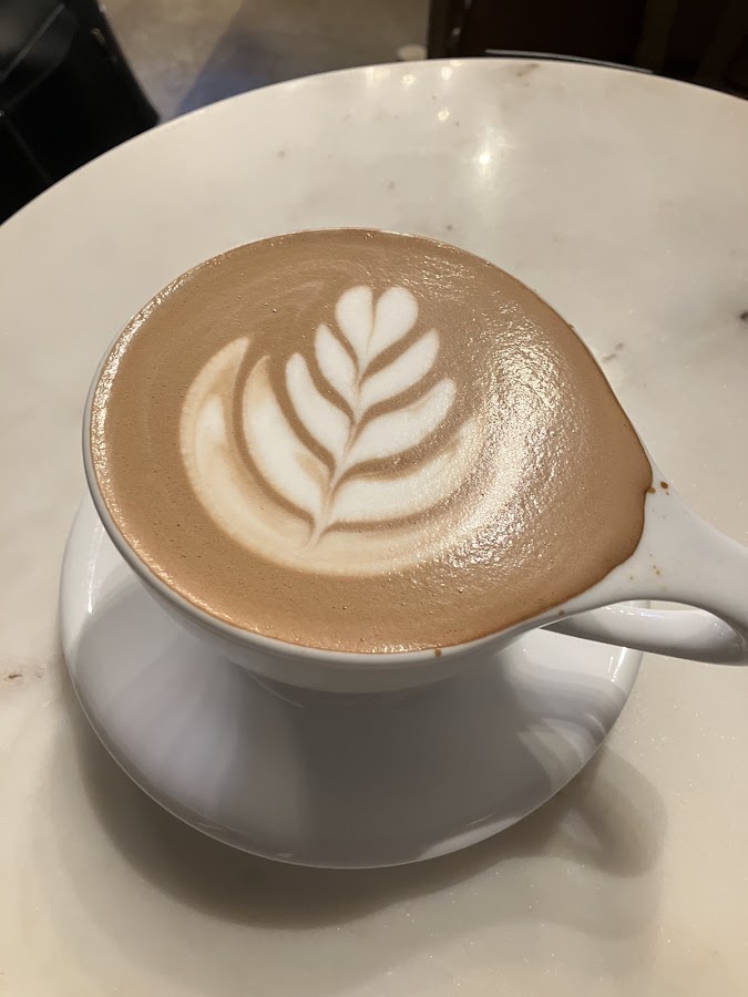 Latte with clean leaf art in white cup