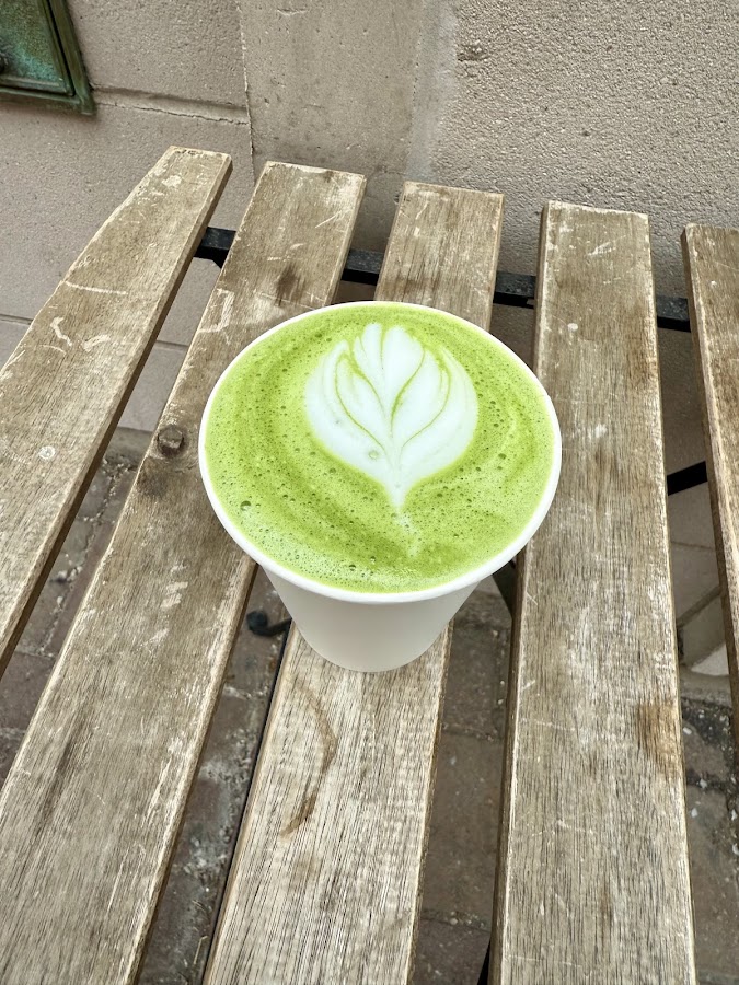Matcha latte with leaf art on outdoor table